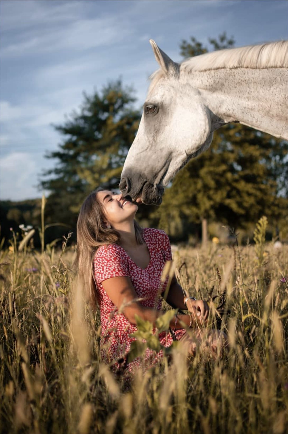 Cavalière et son cheval blanc dans les hautes herbes